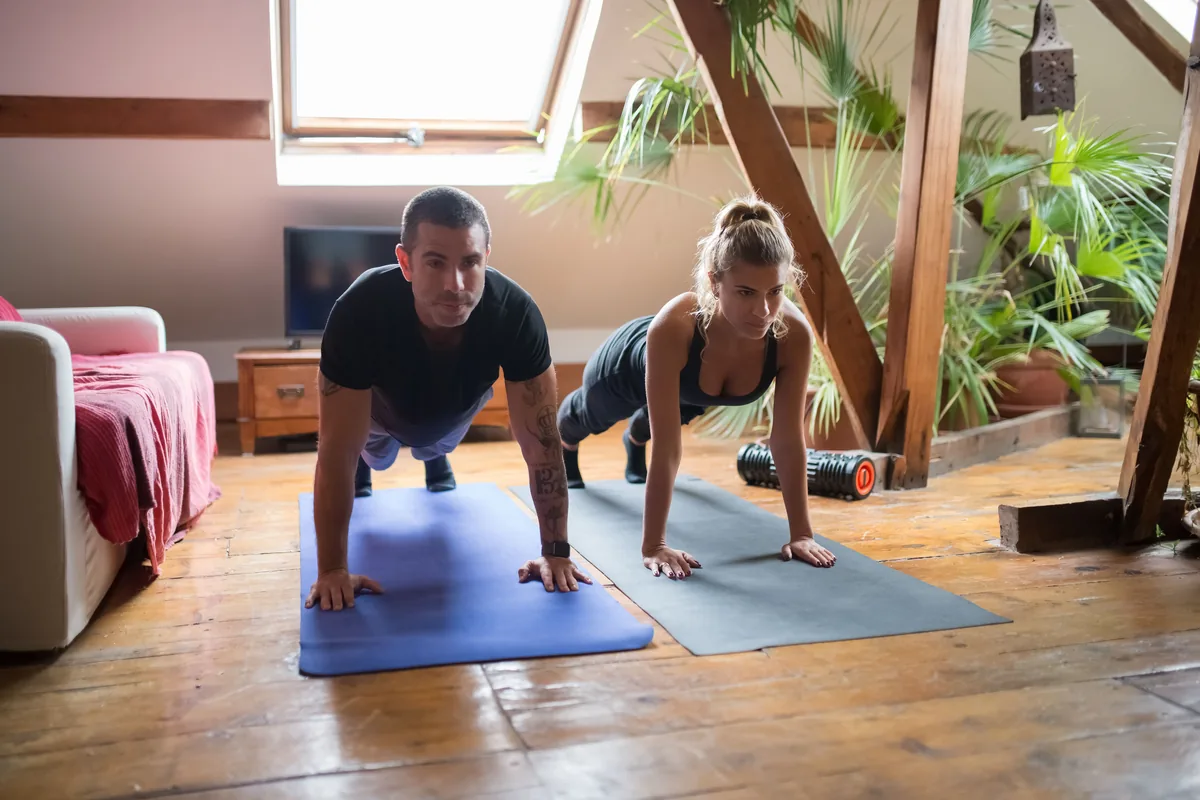 A man and a woman doing push-ups side by side as part of a home workout